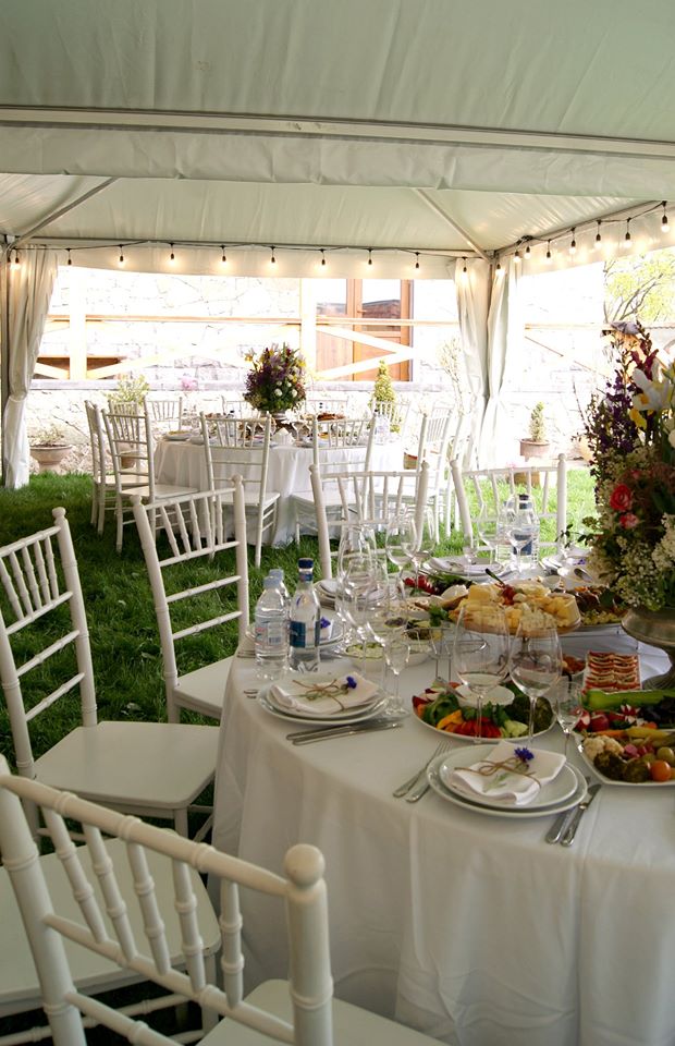 Tented reception with string lights and floral arrangements